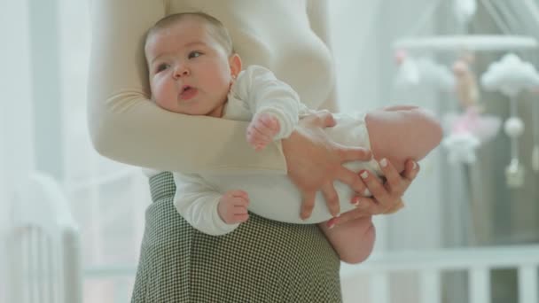 Voor de camera knappe baby zijn in de handen van haar moeder zich gelukkig en ontspannen na de ochtend routine — Stockvideo