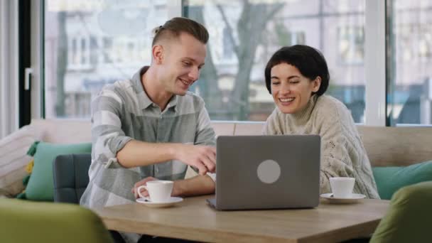 Morgens im Café treffen sich zwei Arbeitskollegen, um am Laptop ein Projekt zu besprechen und den Plan zu analysieren. — Stockvideo