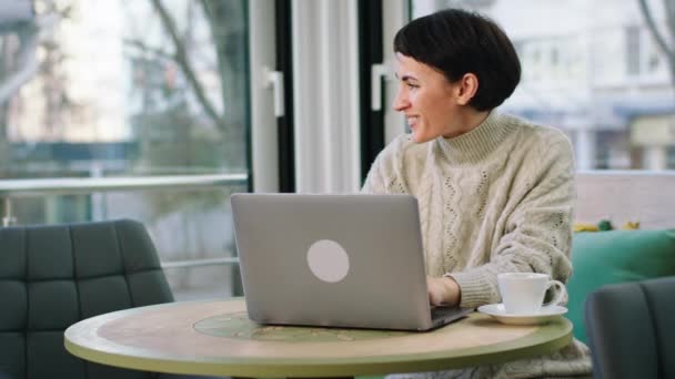 Moderna cafetaria de boa aparência mulher trabalhando on-line a partir do laptop, enquanto tomar seu café da manhã. 4k — Vídeo de Stock