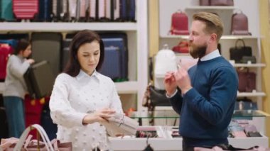 Küçük işletme kavramı ve aksesuar dükkanındaki girişimci güzel müşteri kadın satıcıya çantaların kalitesi hakkında bir konuşma yapar.
