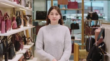 Aksesuar dükkanındaki güzel müşteri bayan kameranın önünde poz veriyor. Sevimli gülümsüyor ve rahatlamış elleri çapraz yapıyor.