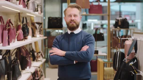 Atractivo vendedor con una gran sonrisa en la tienda de accesorios posando frente a la cámara y cruzando las manos. Disparo en ARRI Alexa Mini. — Vídeos de Stock