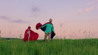 Gülümseyen koca adam ve küçük tatlı oğlu süper kahramanlar gibi birlikte oynuyorlar. Kameranın önünde koşuyorlar ve birlikte eğleniyorlar.