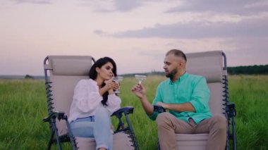 Doğanın tadını çıkarın. Bir kadeh şampanyayla muhteşem bir çiftin şerefine ve tarlanın ortasında sandalyelerde otururken kocaman bir gülümsemeyle. ARRI Alexa Mini 'de çekilen.