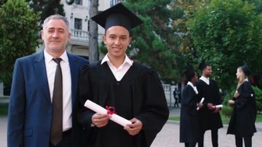 Kameranın önünde karizmatik üniversite müdürüyle birlikte poz veren diplomalı heyecanlı bir mezun. ARRI Alexa Mini.