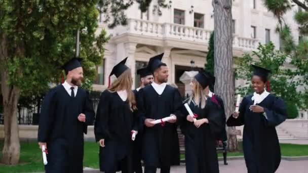 Nowoczesny college park grupa absolwentów wielorasowych studentów po ukończeniu szkoły chodzenia przed kamerą i dyskusji posiadania dyplomów uśmiechnięty duże i uczucie podekscytowany. Strzał na ARRI Alexa — Wideo stockowe