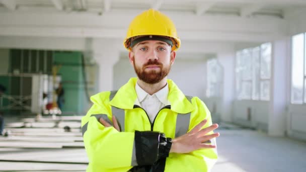 Kameranın önünde el ele tutuşarak poz veren yakışıklı inşaat işçisi inşaat alanında güvenlik kaskı ve ekipman takıyor. — Stok video