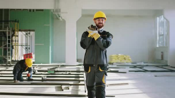 Bom trabalhador de construção de equipamentos andando no canteiro de obras e segurando o conceito de materiais de construção de construção moderna — Vídeo de Stock