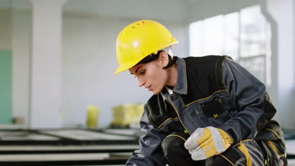 Úžasný mladý žena konstruktér pracovník na staveništi ona pracuje soustředěný a nosí bezpečnostní přilbu a speciální uniformu — Stock video