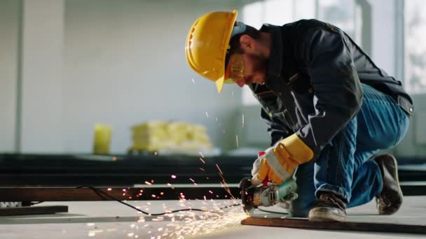 In der großen Baukonstruktion vor der Kamera schneidet Bauarbeiter mit einer Scheibenschweißmaschine einige Metalle und erzeugt die großen Funken — Stockvideo
