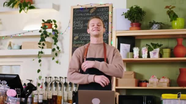 Velmi útulný kavárna před kamerou pracující barista na notebooku pak vstal a pózovat na kameru zkřížit ruce a usmívat se. Shot na ARRI Alexa Mini. — Stock video