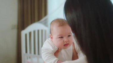 Güzel bir kız bebek sabah annesinin ellerinde birlikte oynuyorlar anne bebeğe çok dikkatli ve güzel sarılıyor