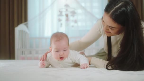 Nursing and maternity concept pretty baby girl and her mother speeding time together laying down on the bed and playing together — Stock Video