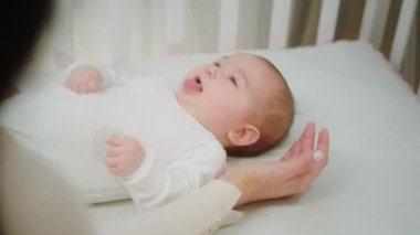 Anne kızına dikkatlice dokunurken tatlı bir kızın bebek karyolasına uzanması fikri.