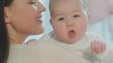Sabahları annesinin kollarında güzel bir bebeğin sevgi dolu bir şekilde sarılmasının ve birlikte iyi vakit geçirmesinin kamera detaylarına yakın.