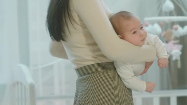 Schöne süße Baby-Mädchen sind in den Armen ihrer Mutter und fühlen sich entspannt im Schlafzimmer vor der Kamera — Stockvideo