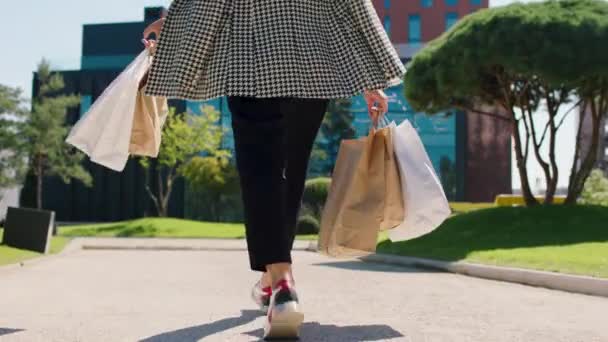 Detalles tomando el primer plano de la parte posterior de una trabajadora de oficina con algunas bolsas de compras de vuelta a su trabajo al centro de negocios principal — Vídeos de Stock