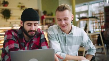 Kameranın önündeki kafe çekici ve karizmatik iki arkadaş laptoplarını kullanarak bir adamın sıcak bir şeyler içmesini izlemek için iyi vakit geçiriyorlar.