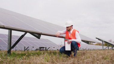 Güneş enerjisi istasyonunda yenilenebilir enerji kavramı genç ekoloji mühendisi güneş panelleri hakkında bilgi yazmak için dijital tablet kullanıyor
