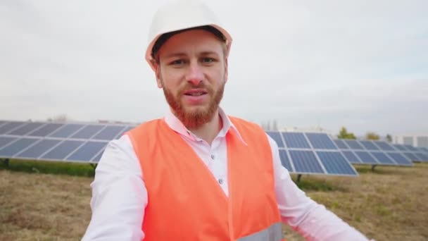 Glad ekologisk ingenjör ta en selfie video om solpaneler solceller batterier han fånga det stora fältet av solpaneler gård i slutet han visar en stor som. Skjuten på ARRI Alexa Mini. — Stockvideo