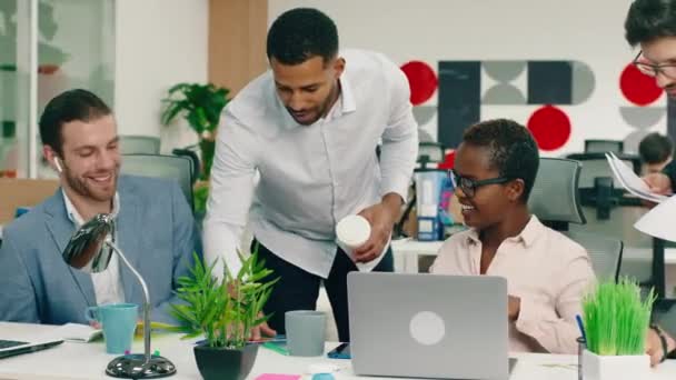 Çok yakışıklı bir siyah adam iki iş arkadaşıyla konuşuyor ve masanın üzerindeki kağıtta bazı şeyler gösteriyor, çok güzel dekore edilmiş bir ofisteler. Arri Alexa Mini. — Stok video