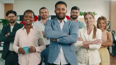 Bir grup iş arkadaşı çok hoş görünümlü bir ofiste gülümsüyor ve kollarını kavuşturuyorlar.