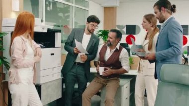 Gri sakallı ve saçları olan yaşlı çekici bir adam işleriyle ilgili tavsiyelerde bulunarak işçilerine yardım ediyor. O otururken etrafını sarıyorlar.