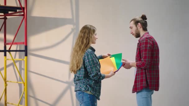 Hermosa pareja caucásica que elige el color para pintar la pared juntos analizando la paleta de colores, todos son equipos para comenzar la pintura. — Vídeos de Stock