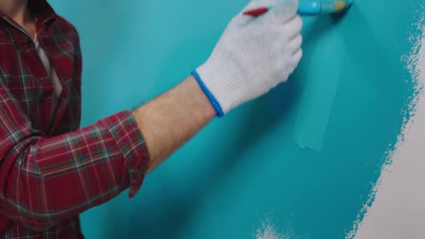 파란색 옷을 입은 남자가 페인트를칠 할 때 보호용 장갑을 끼고 있는 모습으로 그린 작은 붓으로 그린 그림을 비디오로 찍는 모습 — 비디오