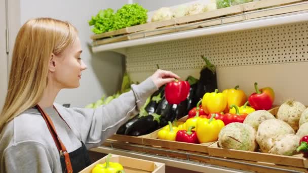 Ekologické potraviny koncept v obchodě s ekologickou zeleninou prodavačka vzít nějaké čerstvé sladké papíry a nahradit je do regálů — Stock video