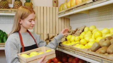 Kameranın önünde sebze dükkanındaki güzel bayan satıcı biraz olgun limon al ve onları raflara yerleştir.