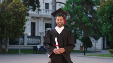 Yakışıklı siyahi adam mezuniyet gününde diplomasıyla kameranın önünde poz vererek mezun oldu.