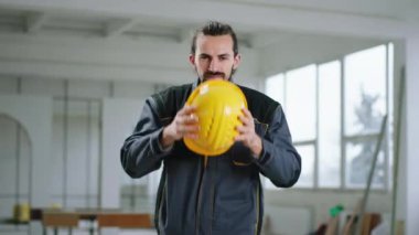 Kameranın önünde poz veren modern inşaat alanı. Güvenlik kaskı takan ve el ele tutuşan iyi görünümlü inşaat işçisi.