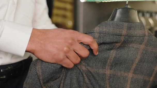 Small business concept in suit shop neemt video close-up klant man neemt een nieuw pak uit de nieuwe collectie van de winkel — Stockvideo