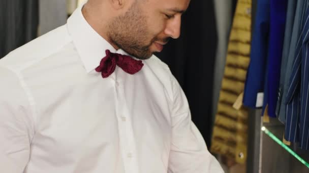 Al negozio di abiti di lusso Afro American uomo cerca di scegliere un buon abito dalla nuova collezione guarda dritto al vestito e sentirsi grande concetto di abbigliamento per piccole imprese e materiali fatti a mano — Video Stock