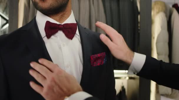 Primer plano de la cámara joven y carismático novio hombre preparándose para la boda el hombre de diseño tratando de usar un mejor traje negro de la nueva colección — Vídeos de Stock