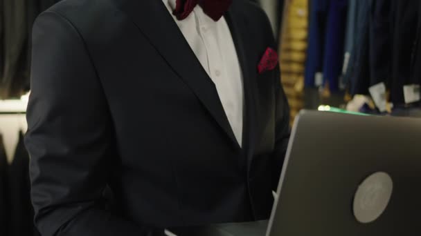Koncept malého obchodního ateliéru ručně vyráběné vyhovuje designér muž Afro American hledá pomocí notebooku zkontrolovat prodej nové kolekce obleků — Stock video