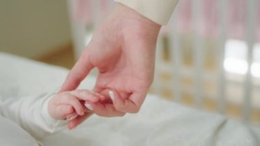 Mutlu gülümseyen küçük bebek yatağında uzanırken yetişkin bir anne ve bebek çocukluğu konseptiyle oynuyor.