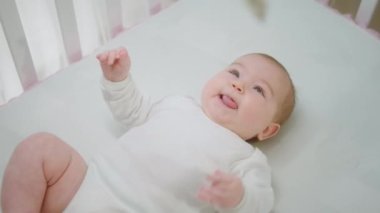 Çok heyecanlı bir kız bebek bebek oyuncaklara bakıyor ve kameranın önünde dilini gösteriyor.