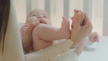 Sabahları genç anne günlük rutininden sonra bebeğin bacaklarını tutar ve sevgiyle bacakları öperdi.