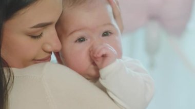 Genç ve çekici anne ve bebeği kameranın önünde dikiliyor ve sevgiyle sarılıyorlar.