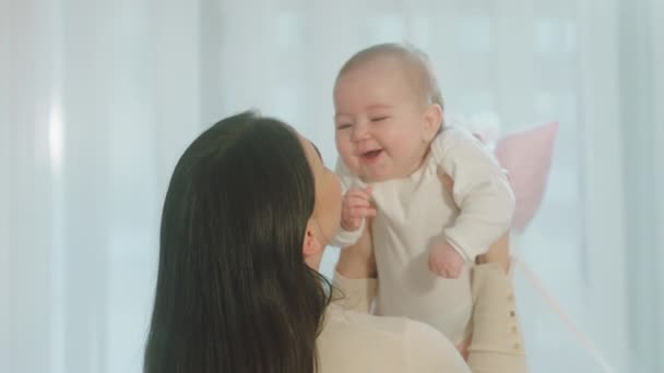 Sorrindo grande bonito e bonito bebê menina enquanto sua mãe segurando-a nos braços e falando com amor menina estão sorrindo grande. 4k — Vídeo de Stock