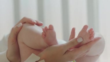 Genç annenin elleri, günlük rutin çocukluk ve annelik kavramından önce sabahları bebek bacaklarını dikkatlice tutuyor. ARRI Alexa Mini 'de çekilen.
