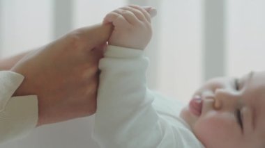 Çocukluk ayrıntıları, sabah yatak odasında genç annelerin el ele tutuştuğu kameraya çok yakın. 4k