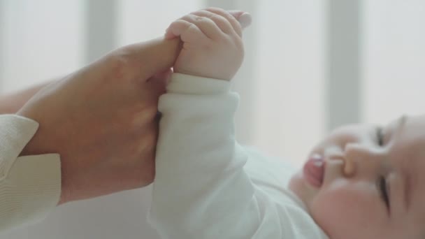 Conceito de detalhes da infância close-up para as mãos da jovem mãe câmera segurando as mãos bonitos do bebê no quarto pela manhã. 4k — Vídeo de Stock
