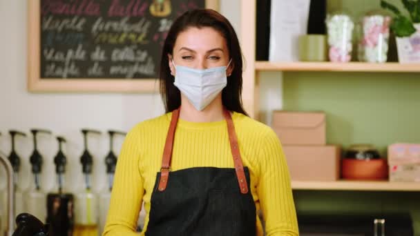 Koncept malého podnikání a podnikatel majitel kavárny žena pózující v kavárně před kamerou ona sundat její ochrannou masku a usmívat se ve velké pandemii — Stock video