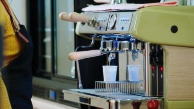 Küçük işletme konsepti barista kadın profesyonel kahve makinesinde müşteriye doğal kahve hazırlıyor.