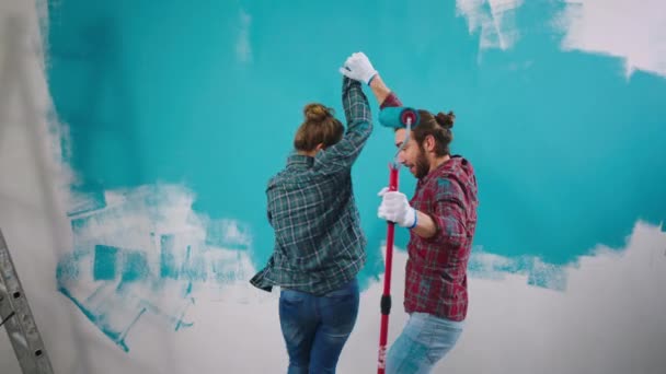 Beau couple à la maison tout en peignant les murs en dansant et profiter du temps en utilisant le pinceau pour s'amuser à s'embrasser — Video