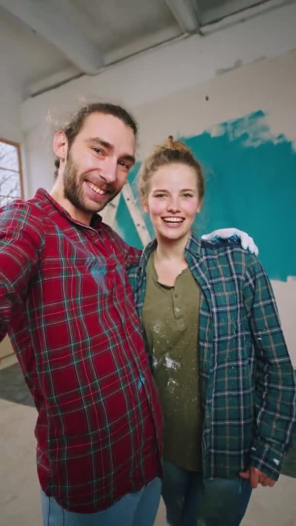 Casal caucasiano juntos enquanto pintam as paredes fazer uma pausa e fazer um vídeo selfie com câmera eles olhando em linha reta sorrindo grande e se sentindo animado em uma nova casa — Vídeo de Stock