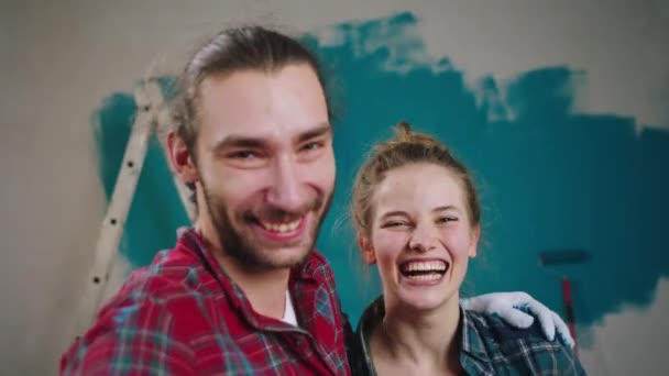 壁に絵を描きながら家で興奮したカップルは、カメラに別れを告げると、彼らはカメラに議論し、非常に興奮した顔を持っているカメラで記憶のためのビデオを取ります.4k — ストック動画